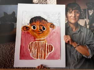 Das Foto zeigt Margit Schötschel, die eine Porträt-Malerei von einem Künstler aus Lobetal präsentiert.